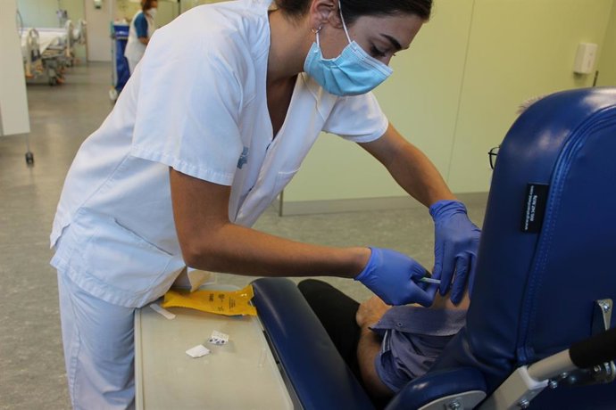 Una sanitaria administra una dosis de vacuna a un paciente