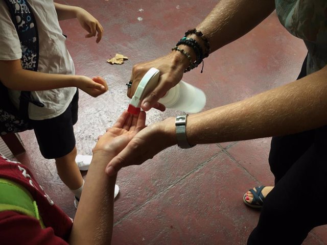 Archivo - Una maestra dispensando gel hidroalcohólico a unos alumnos en el primer día del curso 2021-2022 en el Institut Escola Londres de Barcelona