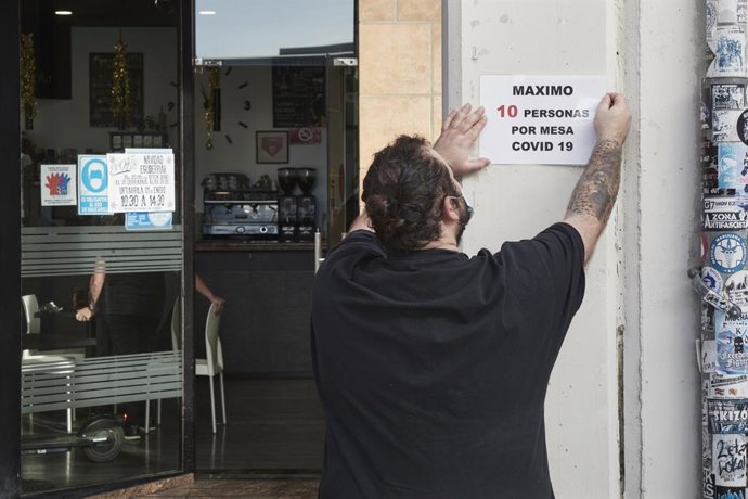 Archivo - Un camarero coloca un cartel de reducción de aforo por Covid, en su bar el día en que han entrado en vigor nuevas restricciones por el coronavirus, a 29 de diciembre, en Pamplona, Navarra, (España). Desde hoy Navarra se convierte en una de las