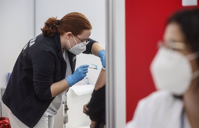 Una sanitaria vacuna a una persona con la tercera dosis de la vacuna de Moderna en el vacunódromo instalado en la Ciutat de Les Arts i les Cincies, que ha reabierto hoy sus puertas, a 31 de enero de 2022, en Valencia, Comunidad Valenciana (España).