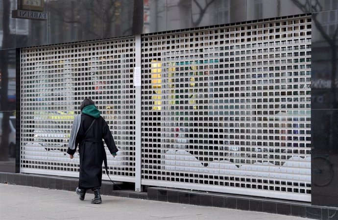 Archivo - 22 November 2021, Austria, Vienna: A passer-by walks past a closed shop. Since Monday 22 November 2021 Austria is in a fourth lockdown. Only shops for daily needs are open, cultural activities are at rest, museums and cinemas are closed. Photo