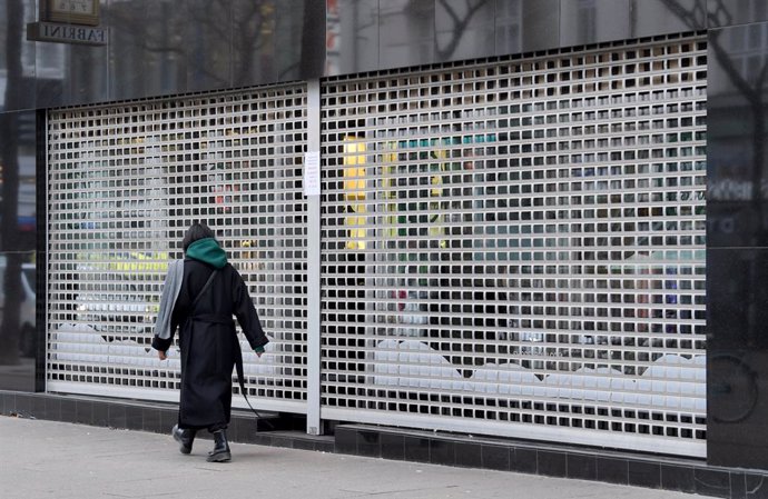Archivo - 22 November 2021, Austria, Vienna: A passer-by walks past a closed shop. Since Monday 22 November 2021 Austria is in a fourth lockdown. Only shops for daily needs are open, cultural activities are at rest, museums and cinemas are closed. Photo