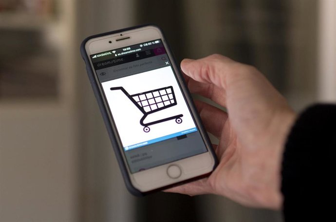 Archivo - Una persona compra a través de su teléfono móvil el día en que dan comienzo las Rebajas Online, a 3 de enero de 2022, en Madrid, (España).