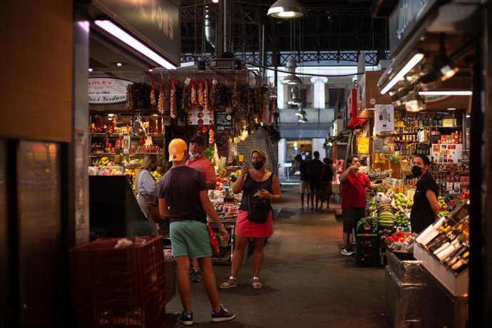Archivo - Una mujer hace una foto a un joven en el mercado de La Boquería, a 5 de agosto de 2021, en Barcelona.