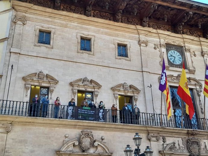 El alcalde de Palma, José Hila, y el presidente de la AECC en Baleares, José Reyes, cuelgan una pancarta en la fachada de Cort con motivo del Día Mundial Contra el Cáncer.