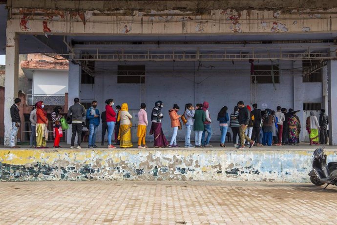 Personas hacen cola frente a un centro de vacunación contra el coronavirus en India