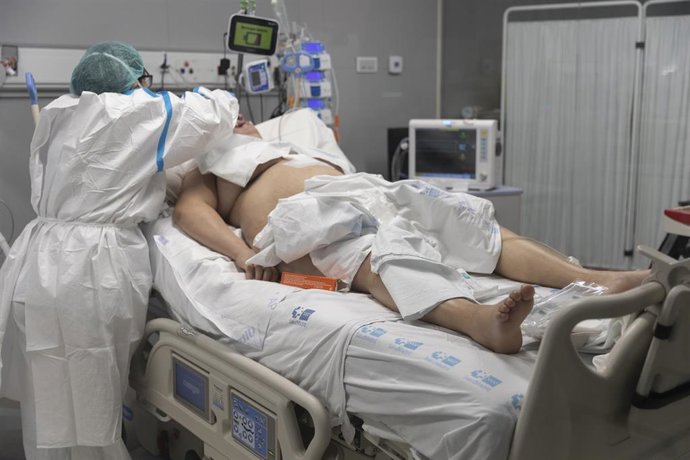 Una sanitaria alrededor de un paciente ingresado en la UCI.