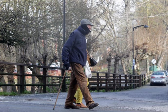 Un home amb bastó camina pel Parc Dos Comtes on la seva llacuna s'ha congelat per les baixes temperatures en Monforte de Lemos a Galícia (Espanya)