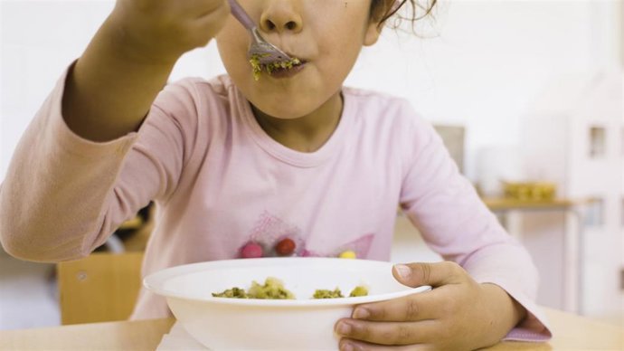 Archivo - Una niña comiendo en el comedor escolar.