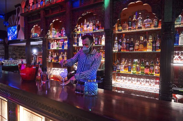 Archivo - Un trabajador prepara una copa en la barra de un bar 