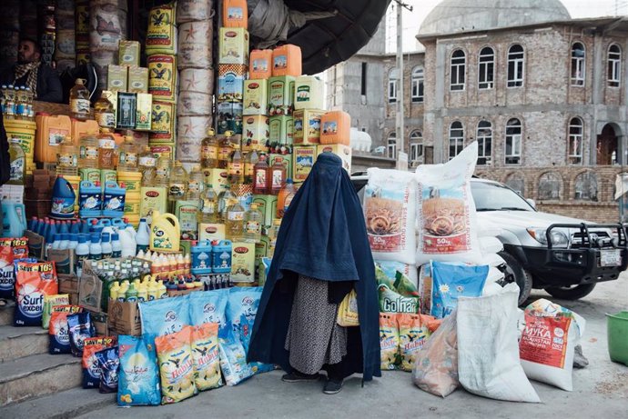 Archivo - Una mujer con burka ante una tienda en Kabul