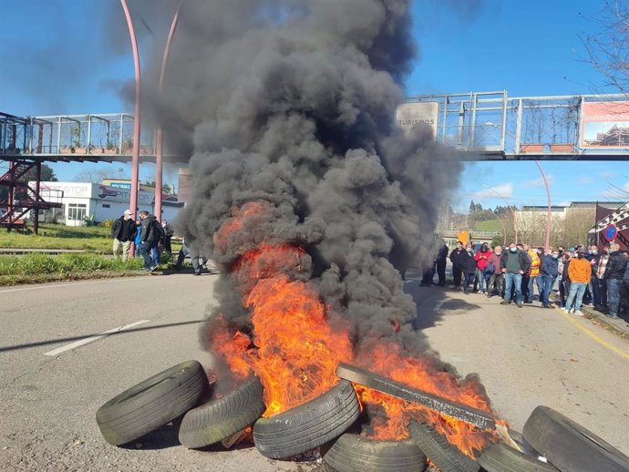 Trabajadores de ArcelorMittal convocados por CCOO y CSI hacen una barricada de neumáticos incendiados a la entrada de la factoría de Avilés
