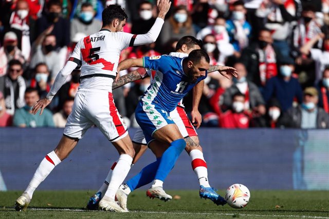 El jugador del Real Betis Borja Iglesias y el futbolista del Rayo Vallecano Alejandro Catena disputan el balón durante un partido en el Estadio de Vallecas de LaLiga Santander 2021-2022.