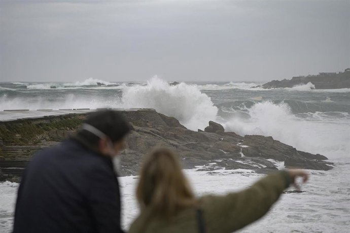 Archivo - Dos personas observan el fuerte oleaje en la costa en A Coruña, a 8 de enero de 2022, en A Coruña, Galicia, (España). La Agencia Estatal de Meteorología activó un aviso naranja que ha ampliado hasta el 10 de enero en todo el litoral  gallego p