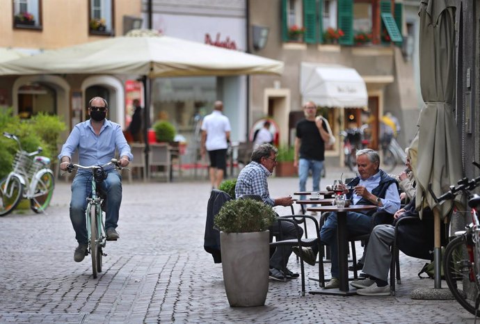 Archivo - 03 June 2020, Italy, Brixen: Aman wearing a face mask rides his bicycle past a street cafe in the old town in Brixen. Italy on Wednesday reopened its borders to visitors from the rest of the European Union and dropped a ban on travel between 