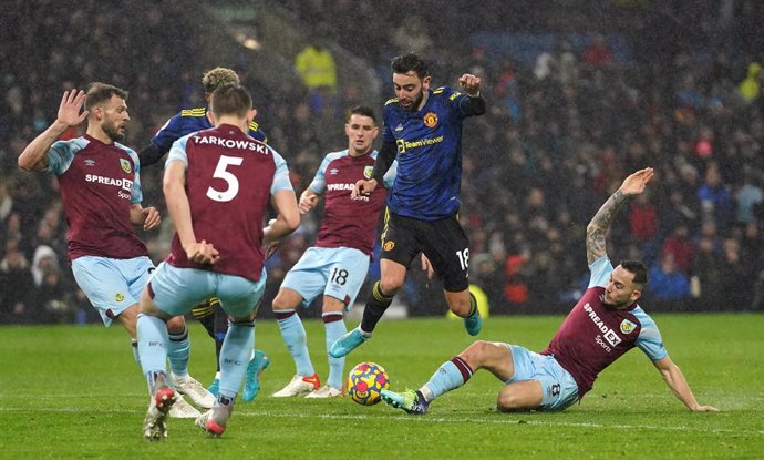 08 February 2022, United Kingdom, Burnley: Manchester United's Bruno Fernandes hurdles a challenge from Burnley's Josh Brownhill (R) during the English Premier League soccer match between Burnley and Manchester United at Turf Moor. Photo: Martin Rickett