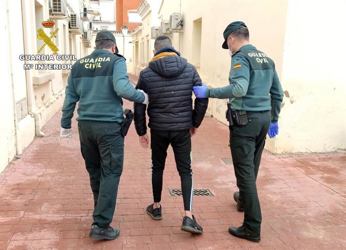 Uno de los detenidos camina junto a dos agentes de la Guardia Civil