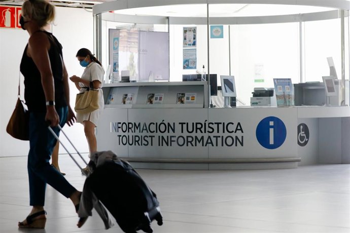 Archivo - Varias personas pasan por delante de una Oficina de Turismo (archivo)