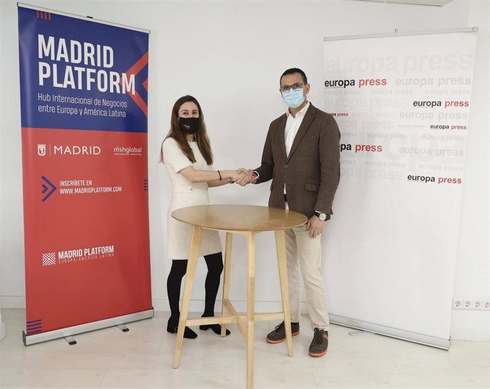 La directora de desarrollo de negocio de Europa Press, Candelas Martín de Cabiedes, y el presidente de Madrid Platform, Carlos Morales, se dan la mano tras firmar un convenio entre Europa Press y  Madrid Platform en las oficinas de la agencia de noticia