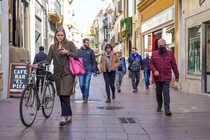 Una mujer en bicicleta y otros ciudadanos sin mascarillas y otro con  ella por la calle Sierpes, , en el primer día sin la obligación de llevar mascarillas por las calle a 10 de febrero del 2022 en Sevilla (Andalucía)