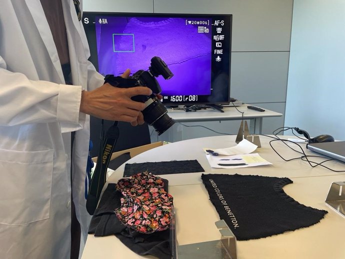 Un agent de la Policia Científica utilitzant la cmera 'Full spectrum' per comprovar les taques de sang en una samarreta