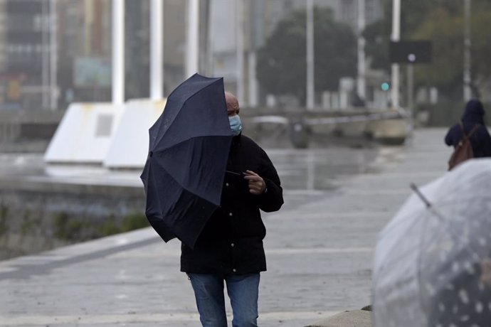 Archivo - Arxivo - Un home amb un paraigua camina pel passeig marítim mentre plou, a 8 de desembre de 2021, a la Corunya, Galícia, (Espanya). La borrasca Barra ha fet que la Xunta hagi activat per a tot el litoral gallec una alerta taronja per temporal 