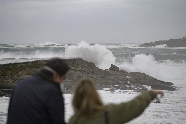 Archivo - Dos personas observan el fuerte oleaje en la costa en A Coruña, a 8 de enero de 2022, en A Coruña, Galicia, (España). La Agencia Estatal de Meteorología activó un aviso naranja que ha ampliado hasta el 10 de enero en todo el litoral  gallego por