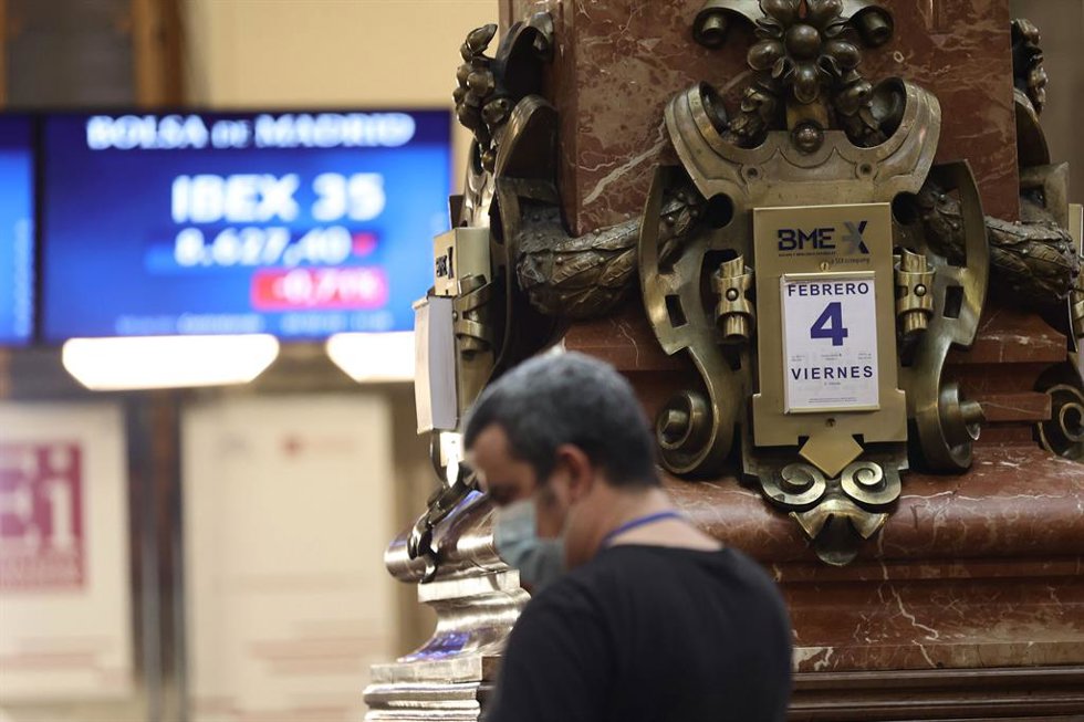 Un hombre delante de un panel con valores del Ibex 35.