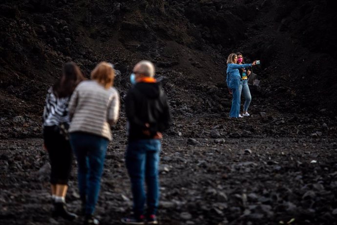 Una pareja de turistas se hacen un 'selfie' sobre la colada de lava del volcán de Cumbre Vieja
