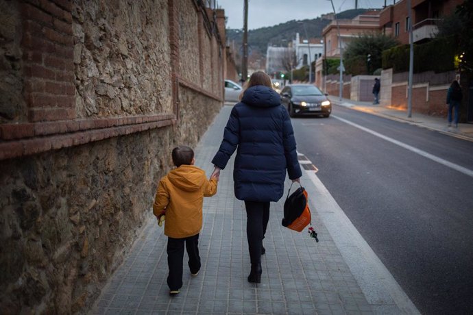 Archivo - Una mujer lleva de la mano a un niño a su primer día de clase presencial tras la Navidad, a 10 de enero de 2022, en Barcelona, Catalunya, (España). Más de 8 millones de alumnos de toda España retoman hoy sus clases tras el periodo vacacional d