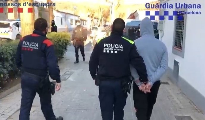 Agents de la Gurdia Urbana i els Mossos d'Esquadra amb un dels detinguts de l'operatiu
