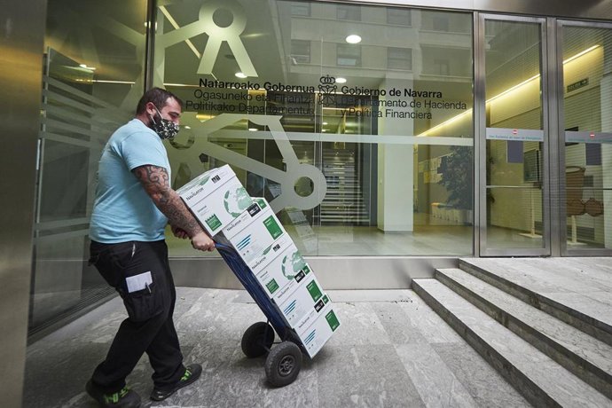 Archivo - Un transportista lleva un carro con cajas 