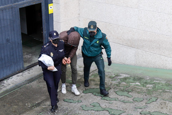 Un agente de Policía Nacional y otro de la Guardia Civil, llevan a uno de los dos detenidos por la brutal paliza a dos jóvenes a finales del mes de enero, a su salida del Juzgado de Vigo, a 15 de febrero de 2022, en Vigo, Pontevedra, Galicia (España). 