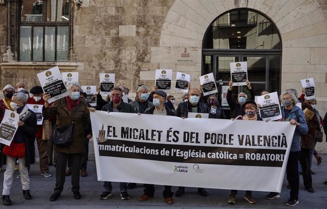 Varias personas se manifiestan, para reclamar los bienes inmatriculados de la Iglesia, con pancaratas que rezan 'El Micalet és del poble valencià' en la Plaza de Manises
