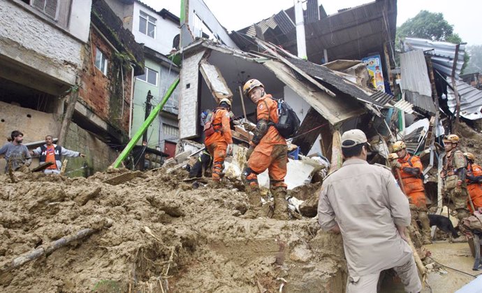 HANDOUT - 16 February 2022, Brazil, Petropolis: Rescue workers inspect the scene in a residential area destroyed by mudslides. The number of people killed in landslides and flooding in the city of Petropolis in Brazil has risen to 44, local media report