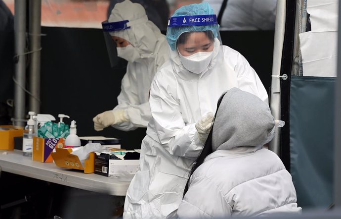 13 February 2022, South Korea, Seoul: Medical workers carry out rapid antigen tests at a COVID-19 testing station, as South Korea hit a daily high of 56,431 new COVID-19 infections.