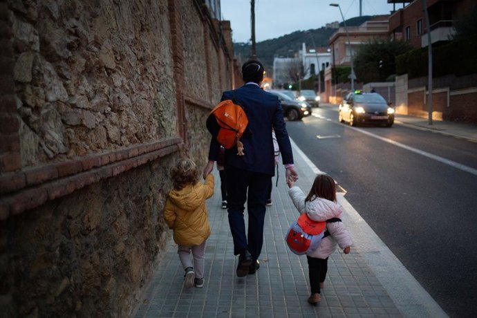 Archivo - Un home acompanya dues nenes a classe