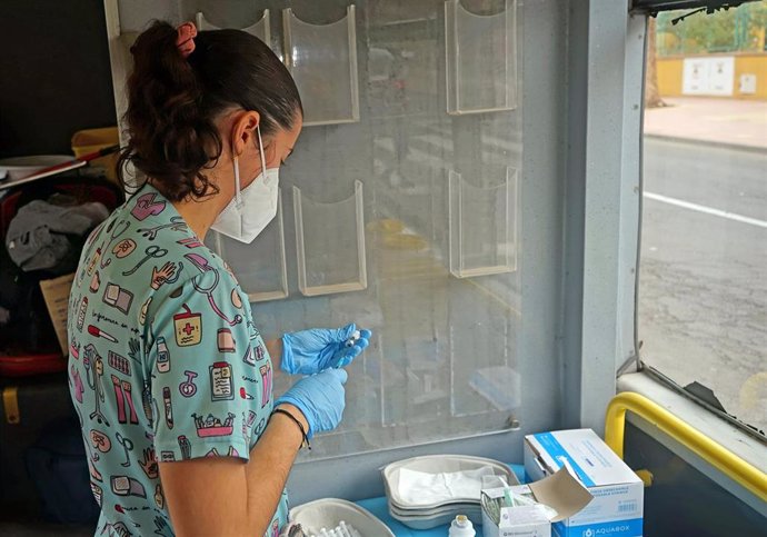 Una sanitaria prepara una vacuna para un niño, en la 'vacuguagua'
