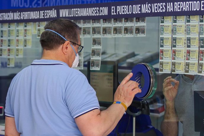 Archivo - Un hombre compra lotería en una administración