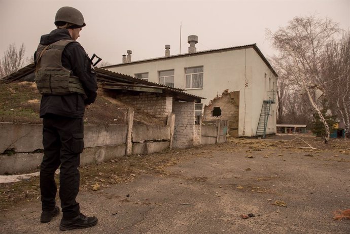 17 February 2022, Ukraine, Stanytsia Luhanska: An armed person in protective clothing stands on the premises of the damaged kindergarten 21. According to the Ukrainian military, the damage to the building was caused by shelling, in which several civilia