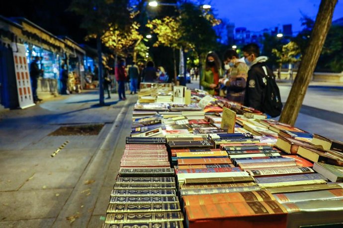Archivo - Varias personas se acercan a los puestos y casetas de libros en la Cuesta de Moyano 
