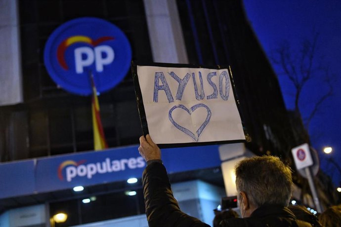 Un hombre sostiene un cartel en el que se lee Ayuso con un corazón