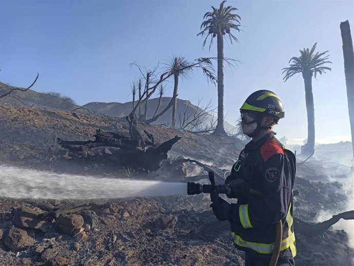 Archivo - Un bombero realiza tareas de enfriamiento en la zona del incendio