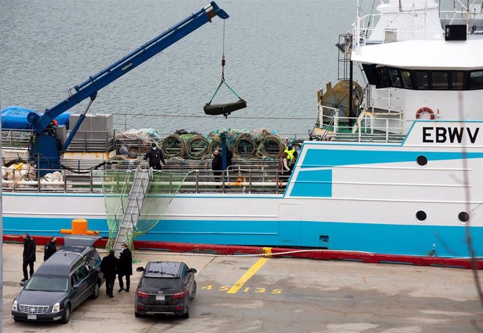 Operarios bajan con la ayuda de una grúa a una de las personas fallecidas en el naufragio del buque gallego, a su llegada al Puerto de San Juan de Terranova, a 19 de febrero de 2022, en San Juan, Terranova (Canadá).