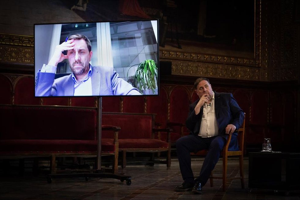 El eurodiputado Toni Comín (Junts), en pantalla, y el líder de ERC, Oriol Junqueras, intervienen en el acto de cierre del ciclo 'Escolta Europa', enmarcado en la Conferencia sobre el Futuro de Europa (Cofoe).