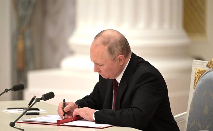 HANDOUT - 21 February 2022, Russia, Moscow: Russian President Vladimir Putin signs a decree recognizing the independence of two breakaway regions in eastern Ukraine, Leonid Pasechnik and Denis Pushilin, controlled by Moscow-backed separatists, during a 