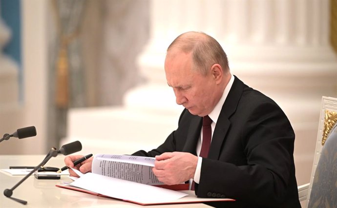 HANDOUT - 21 February 2022, Russia, Moscow: Russian President Vladimir Putin signs a decree recognizing the independence of two breakaway regions in eastern Ukraine, Leonid Pasechnik and Denis Pushilin, controlled by Moscow-backed separatists, during a 