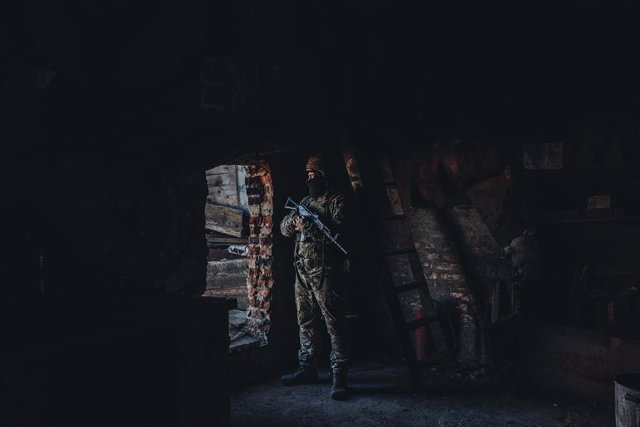 Un soldado ucraniano observa desde el interior de un edificio en su posición militar en un pueblo cercano a la línea de contacto