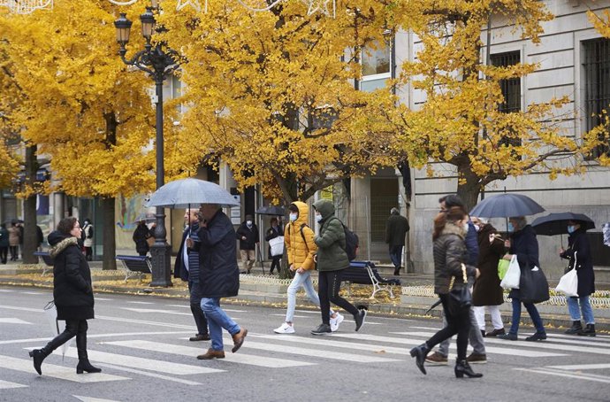 Archivo - Varias personas con paraguas cruzan un paso para peatonesn Santander.