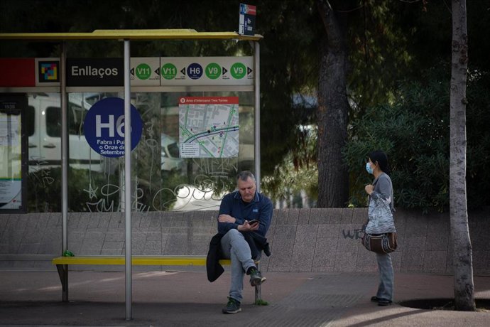 Dos personas esperan el autobús, durante la huelga de autobuses, a 17 de febrero de 2022, en Barcelona, Cataluña, (España). En una foto de archivo.